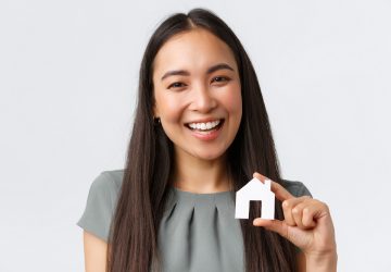 mulher sorridente com uma miniatura de casa na mão