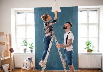 Casal de adultos meados mudando a lâmpada dentro de casa em casa