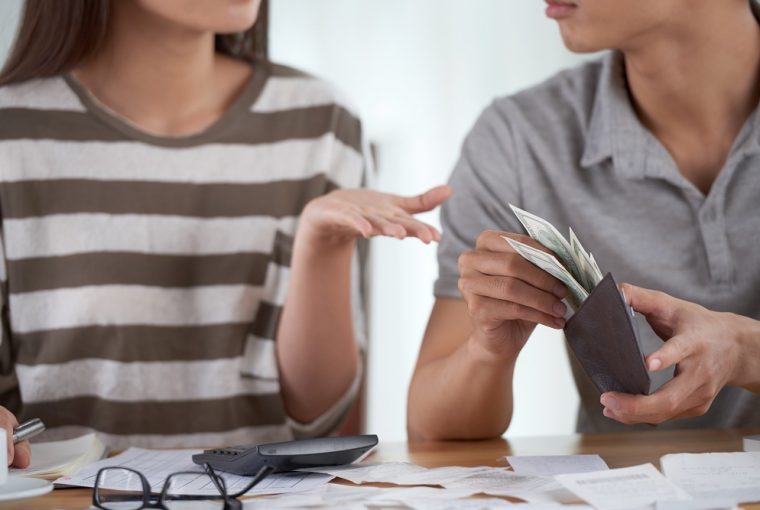 casal organizando as finanças, ele com dinheiro ela com calculadora