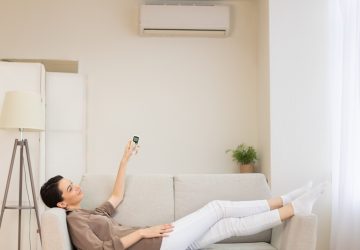 mulher jovem ligando no ar condicionado em sua casa