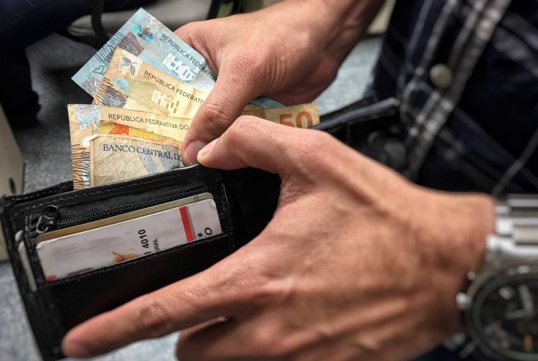carteira mostrando homem colocando dinheiro ao antecipar o 13° salário