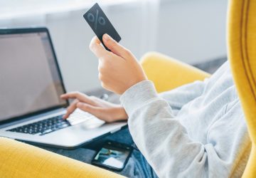 Mãos segurando o cartão de crédito e usando o laptop.