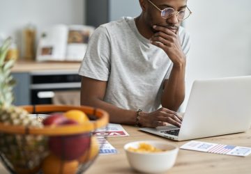 homem afrodescendente mexendo no computador pensando sobre o cadastro positivo