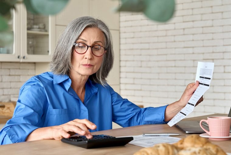 mulher idosa calculando as tarifas mostradas em um papel de banco digital ou tradicional