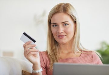 Mulher segurando um cartão, simbolizando como funciona o cartão de crédito