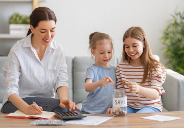 família feliz (mãe e duas filhas) fazendo contas e guardando dinheiro, simbolizando uma vida financeira estável