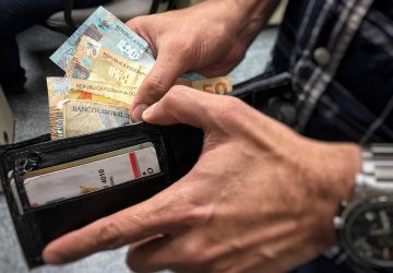 homem colocando dinheiro dentro da carteira, simbolizando o pagamento da restituição do IR 2021