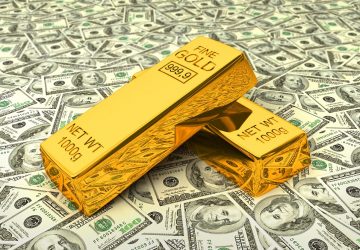 duas barras de ouro sob algumas notas de dólar simbolizando investir em ouro na crise