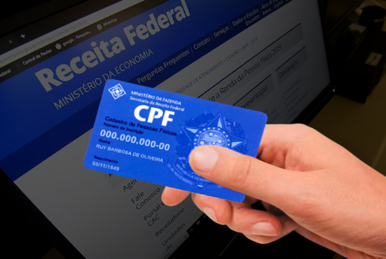 computador ao fundo mostrando o site da Receita Federal e a frente uma mão segurando um cartão de CPF, simbolizando como descobrir o CPF pelo nome