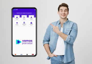 jovem apontando para a tela de um smartphone mostrando o site da Vamos parcelar site para pagar contas parceladas e que ganha cashback