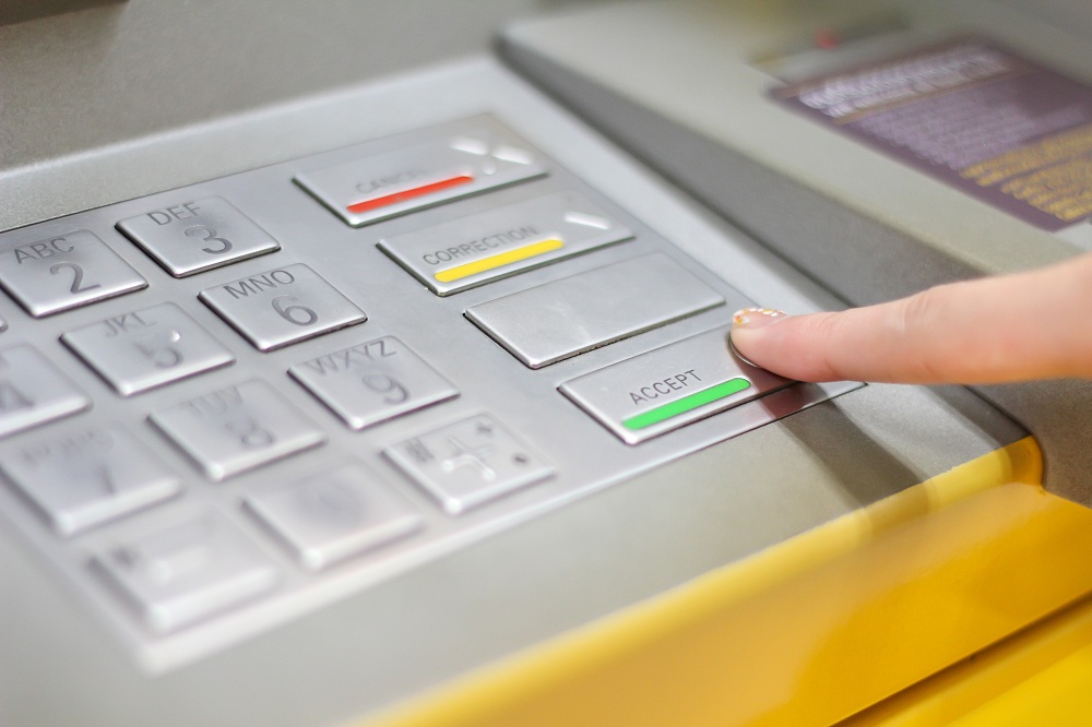 imagem de mulher apertando o botão de confirmar de um caixa eletrônico simbolizando o empréstimo no caixa