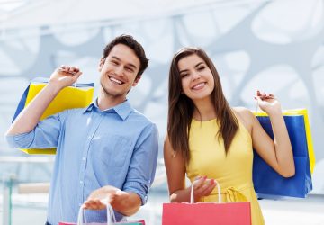 Jovem casal feliz segurando uma sacola de compras que pagaram no crediário