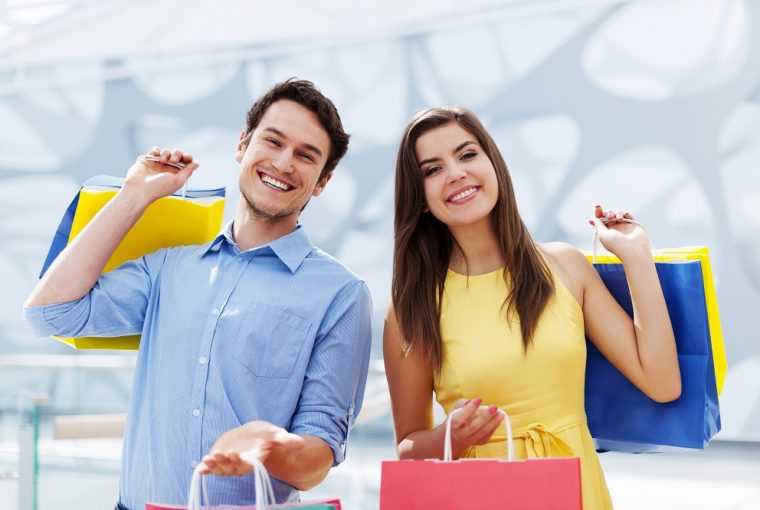 Jovem casal feliz segurando uma sacola de compras que pagaram no crediário