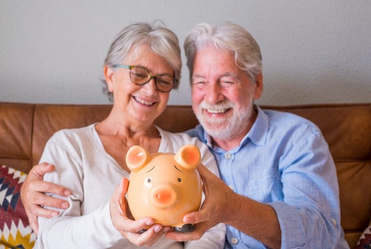 Perto do casal sênior, mostrando o cofrinho para economizar dinheiro. casal de idosos segurando o cofrinho para investimento e o conceito de planejamento futuro. casal feliz aposentado segurando o cofrinho juntos em casa