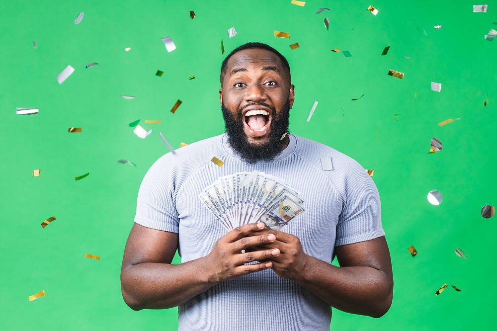 homem feliz e estonteante segurando dinheiro na mão simbolizando como ganhar dinheiro com aplicativos de recompensa