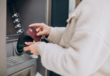 Mulher sacando dinheiro em caixa eletrônico fora da rua da sua conta salário