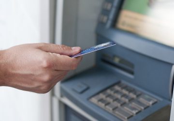 mão de homem fazendo a Inserção manual de cartão atm na máquina bancária para retirar dinheiro simulando a diferença entre conta corrente e conta salário