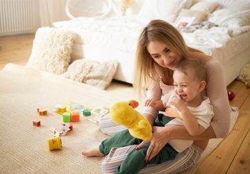 mãe com bebê brincando no chão do quarto, simbolizando o pagamento do salário-maternidade