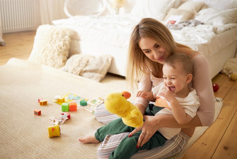 mãe com bebê brincando no chão do quarto, simbolizando o pagamento do salário-maternidade