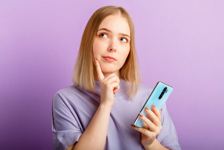 Jovem pensa a dúvida sobre a pergunta usando o smartphone pensando sobre qual é o melhor banco digital