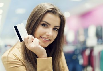 Mulher bonita com cartão de crédito em shopping simbolizando a escolha de qual cartão de loja é mais fácil de aprovar