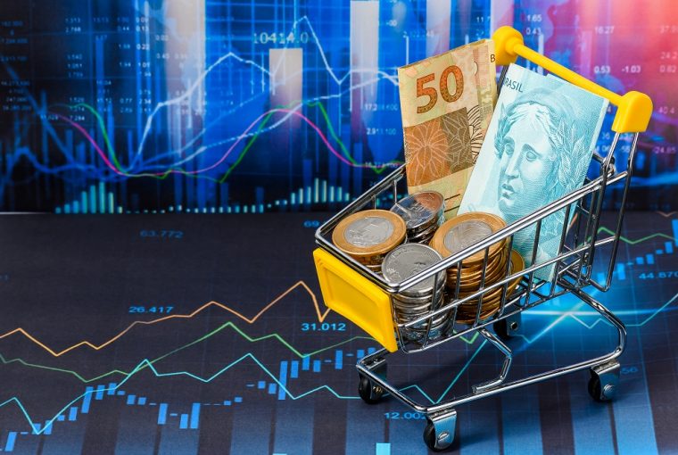 fundo de uma plataforma de Home Broker e um carrinho de compras com notas de cinquenta e cem reais e algumas moedas, simbolizando o passo a passo de como investir com pouco dinheiro