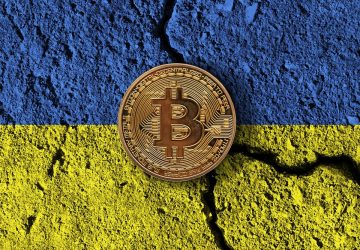 criptomoeda Bitcoin em cima de uma pintura da bandeira da Ucrânia