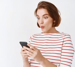 garota surpresa e animada olhando para a tela do celular, fazendo empréstimo com garantia de celular