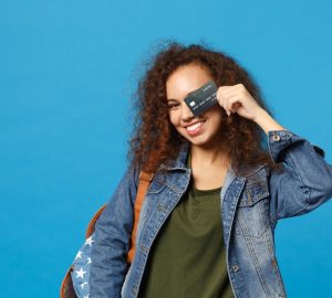 ovem estudante adolescente afro-americana em roupas jeans, mochila segurando cartão de crédito
