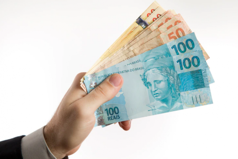 mão masculina segurando notas de dinheiro em Real, simbolizando osEmpréstimos rápidos de aprovar para solicitar agora mesmo