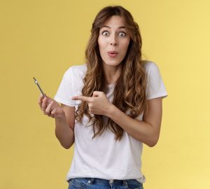 Menina bonita, entusiasmada e impressionada, olhando para o smartphone, simbolizando os Jogos para ganhar dinheiro de verdade em 2022