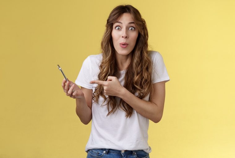 Menina bonita, entusiasmada e impressionada, olhando para o smartphone, simbolizando os Jogos para ganhar dinheiro de verdade em 2022