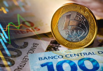 ilustração sendo mostradas notas de cinquenta e duzentos reais e uma moeda de um real em destaque simbolizando a inflação no Brasil